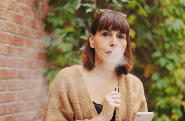 Frau mit einer E-Zigarette an der Backe
