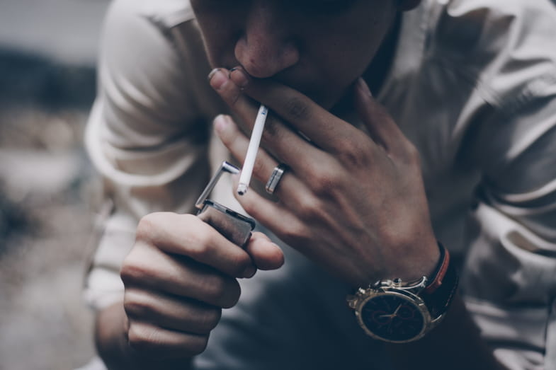 Nikotinsüchtiger Junge zündet sich eine Zigarette an