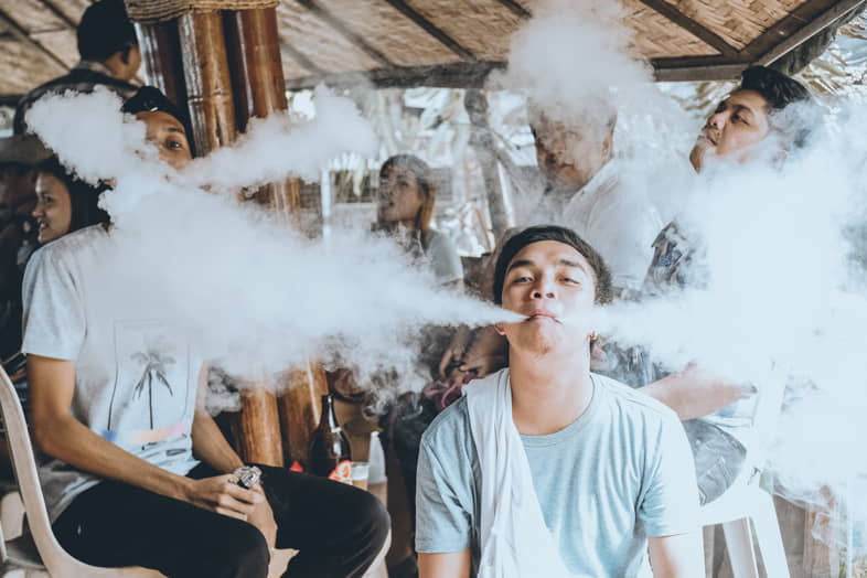 Eine Gruppe junger Leute, die Wolken jagen und große Dampfwolken ausstoßen